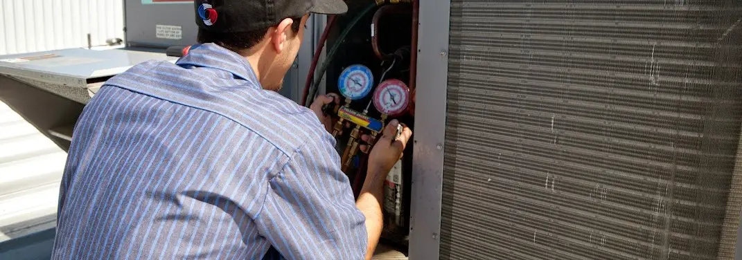 HVAC technician servicing a condenser unit in Ontwa