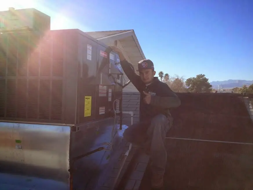 HVAC technician performing Heat Pump Repair on a rooftop unit in Ontwa